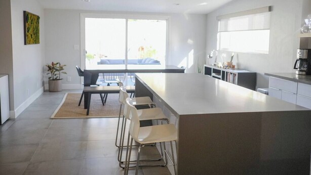 Una cocina moderna con una isla grande, taburetes de bar y un comedor con mesa y sillas.