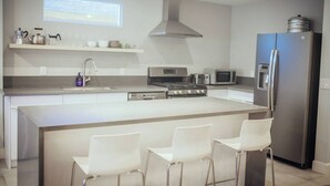 Una cocina moderna con una isla central, electrodomésticos de acero inoxidable y una ventana sobre el fregadero.