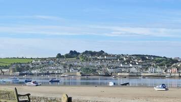 A coastal town with a stone wall, a bench, and boats on the water.