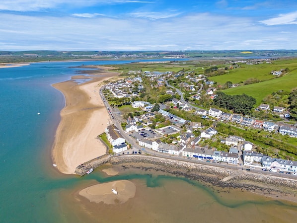 An aerial view of a coastal town with a beach, houses, and a road.