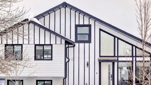A modern building with a sloped roof, large windows, and a visible door. - Cozy 1BR Suite, Sleeps 3, Private Entry + Parking (Calgary)