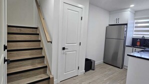 A modern kitchen with a built-in refrigerator, a wooden staircase, and a white door. - Cozy 1BR Suite, Sleeps 3, Private Entry + Parking (Calgary)