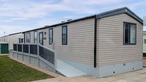 Une rangée de maisons mobiles avec une allée couverte et une pelouse verdoyante.