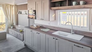 Une cuisine moderne avec des armoires blanches, un plan de travail en bois, un évier encastré et une fenêtre offrant une belle vue.