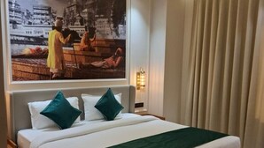 Een net opgemaakt bed met een groene plaid, een groot schilderij aan de muur en een plafondventilator.
