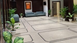 Een ruime lobby met een modern ontwerp, met een zithoek met banken, een groot kunstwerk aan de muur en potplanten.