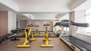 A gym with stationary bikes, a treadmill, and a bench.