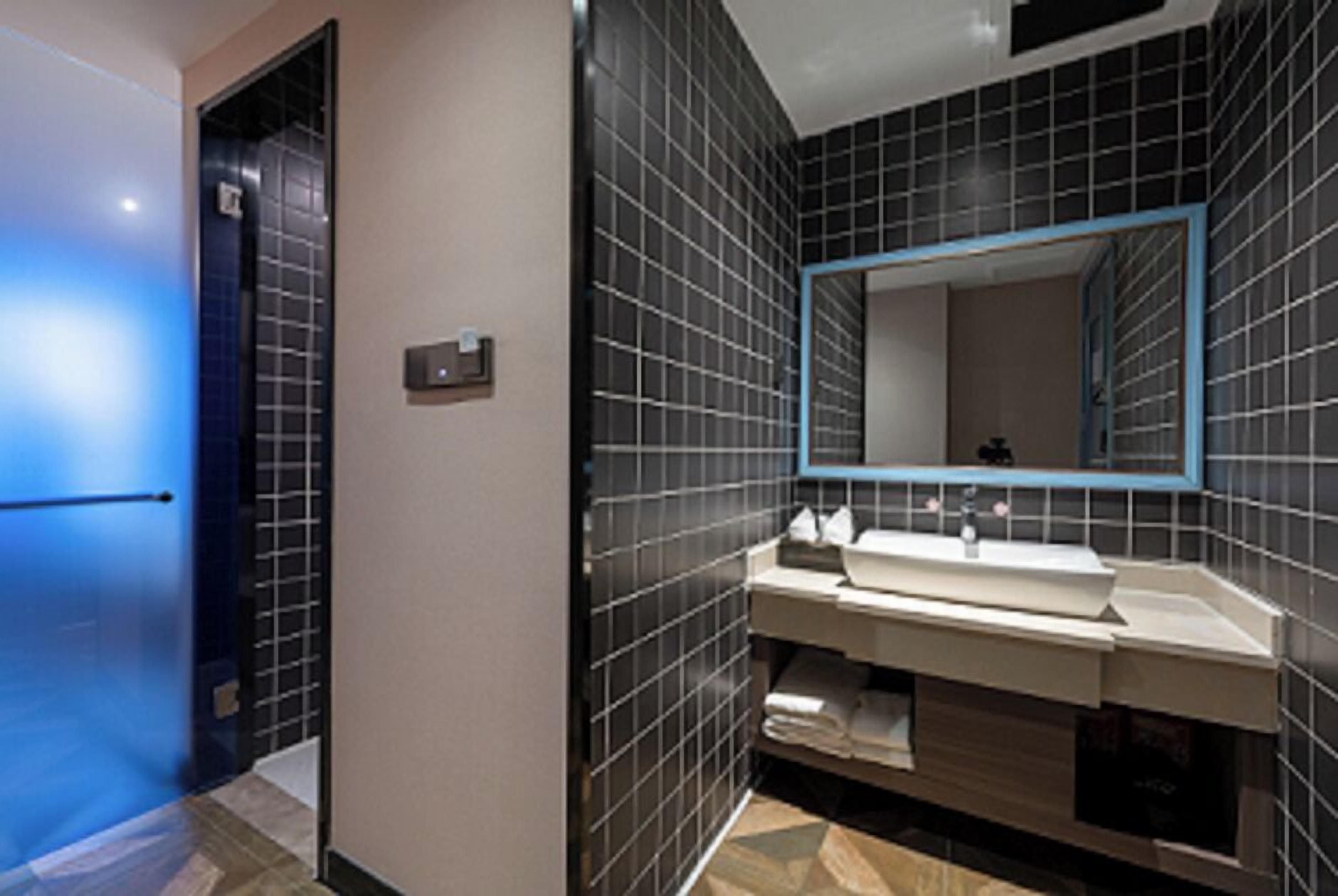A modern bathroom with a large mirror, a sink, and a towel rack.