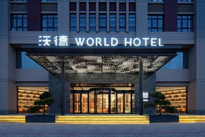 The exterior of the World Hotel with a modern entrance, illuminated signage, and a well-lit facade. - World Hotel Zhengzhou Univ Hi-tec Branch (Zhengzhou)