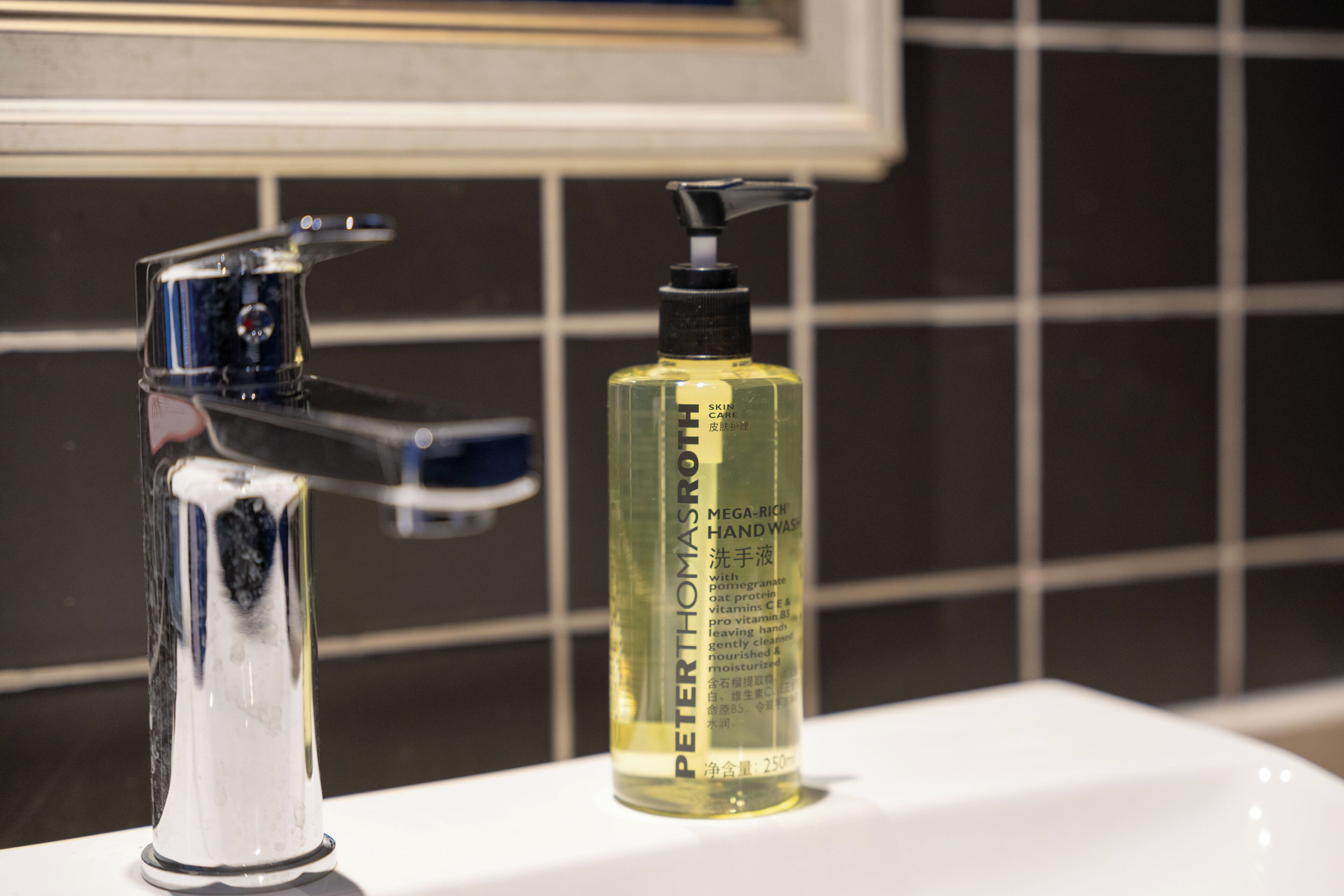 Ein Waschbecken mit einem chromfarbenen Wasserhahn und einer Flasche Peter Thomas Roth Handseife.