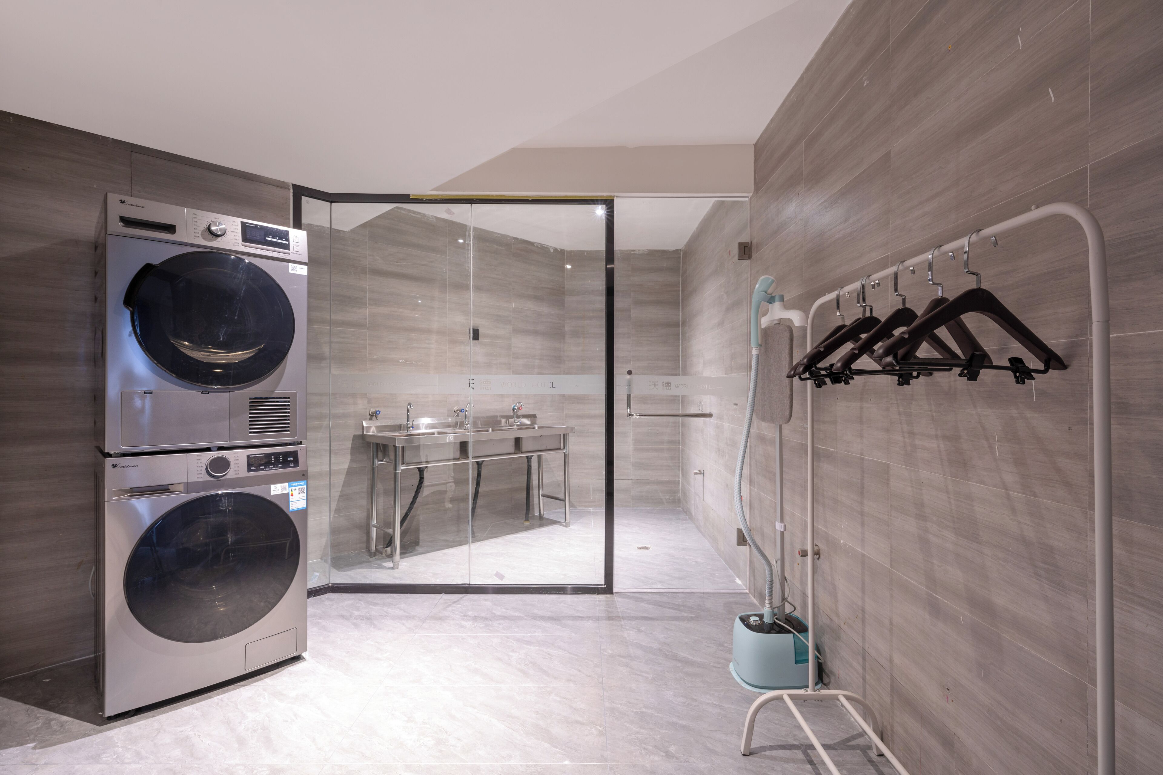 A modern bathroom with a built-in washer and dryer, a glass shower enclosure, and a towel rack.