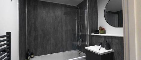 A modern bathroom with a bathtub, a sink, and a mirror.