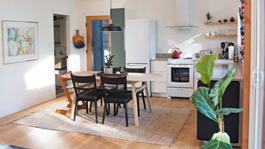 A modern kitchen with white cabinets, a built-in oven, and a hanging pot rack. - Bird House: Fully Renovated Vesuvius Cottage (Salt Spring Island)