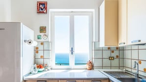 A kitchen with a view of the sea, a refrigerator, cabinets, and a sink. - Casa Cycas by Interhome (Ospedaletti)
