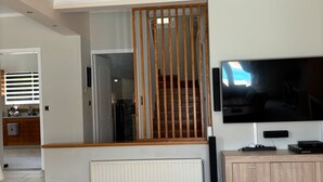 Une chambre moderne avec un grand lit, une télévision, une armoire en bois et un escalier.