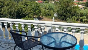 Une terrasse avec une table et des chaises, offrant une vue panoramique sur un paysage pittoresque composé de collines et de bâtiments.