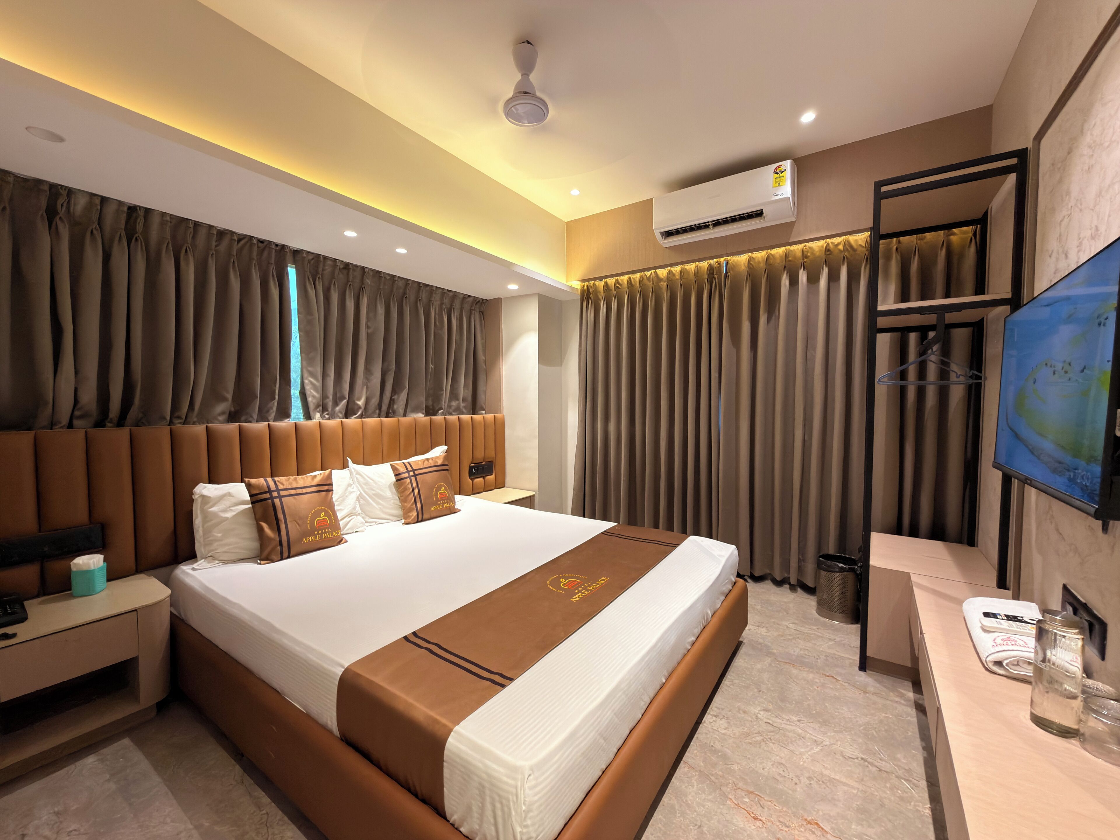 Habitación de hotel con una cama grande, una mesita de noche, aire acondicionado, televisión y un área de baño.