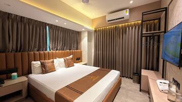 Habitación de hotel con una cama grande, una mesita de noche, aire acondicionado, televisión y un área de baño.