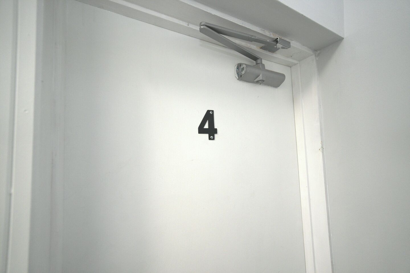 Eine weiße Tür mit der Nummer 4, darüber eine Überwachungskamera.