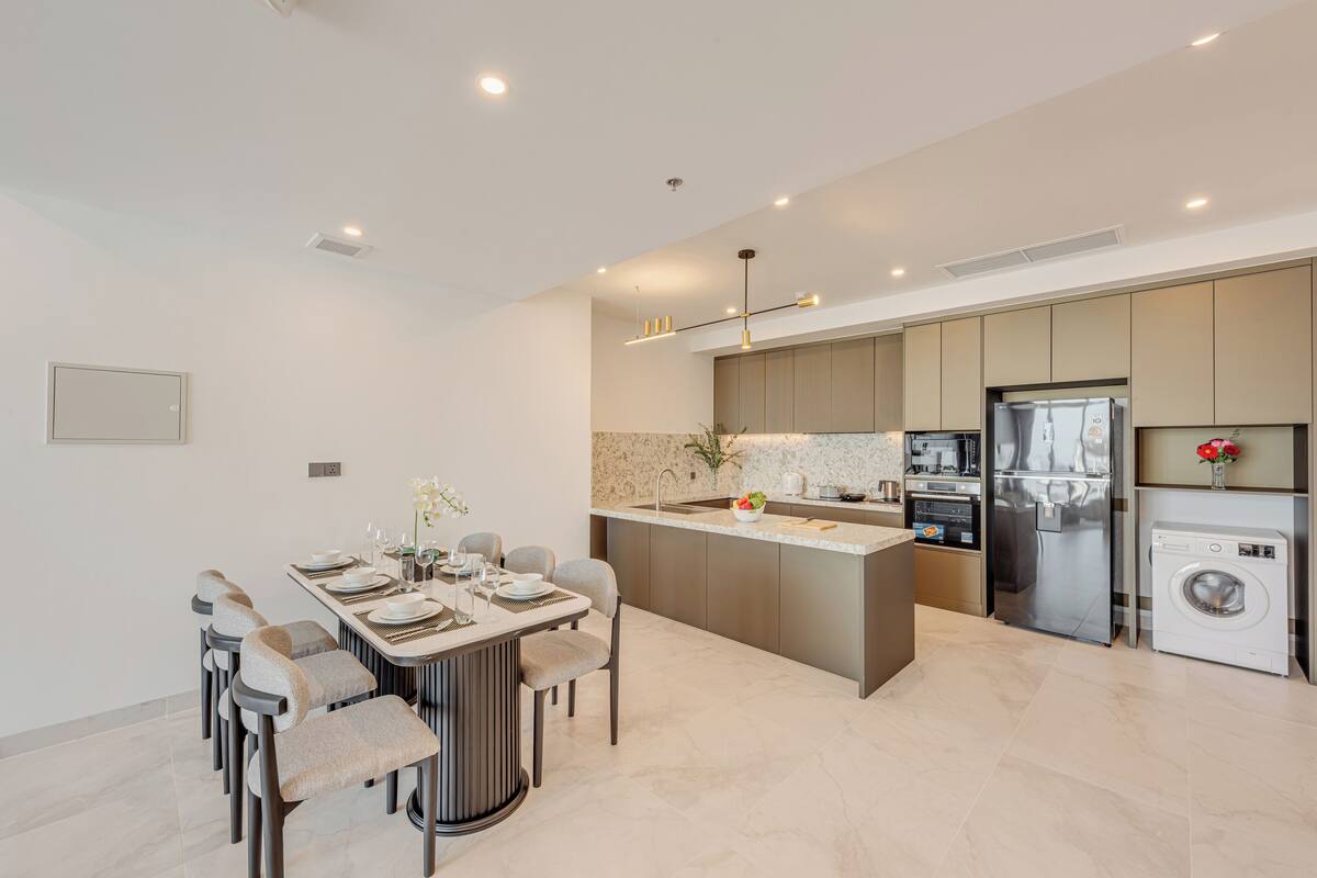 A modern kitchen with a central island, built-in appliances, and a dining area with a table set for four.