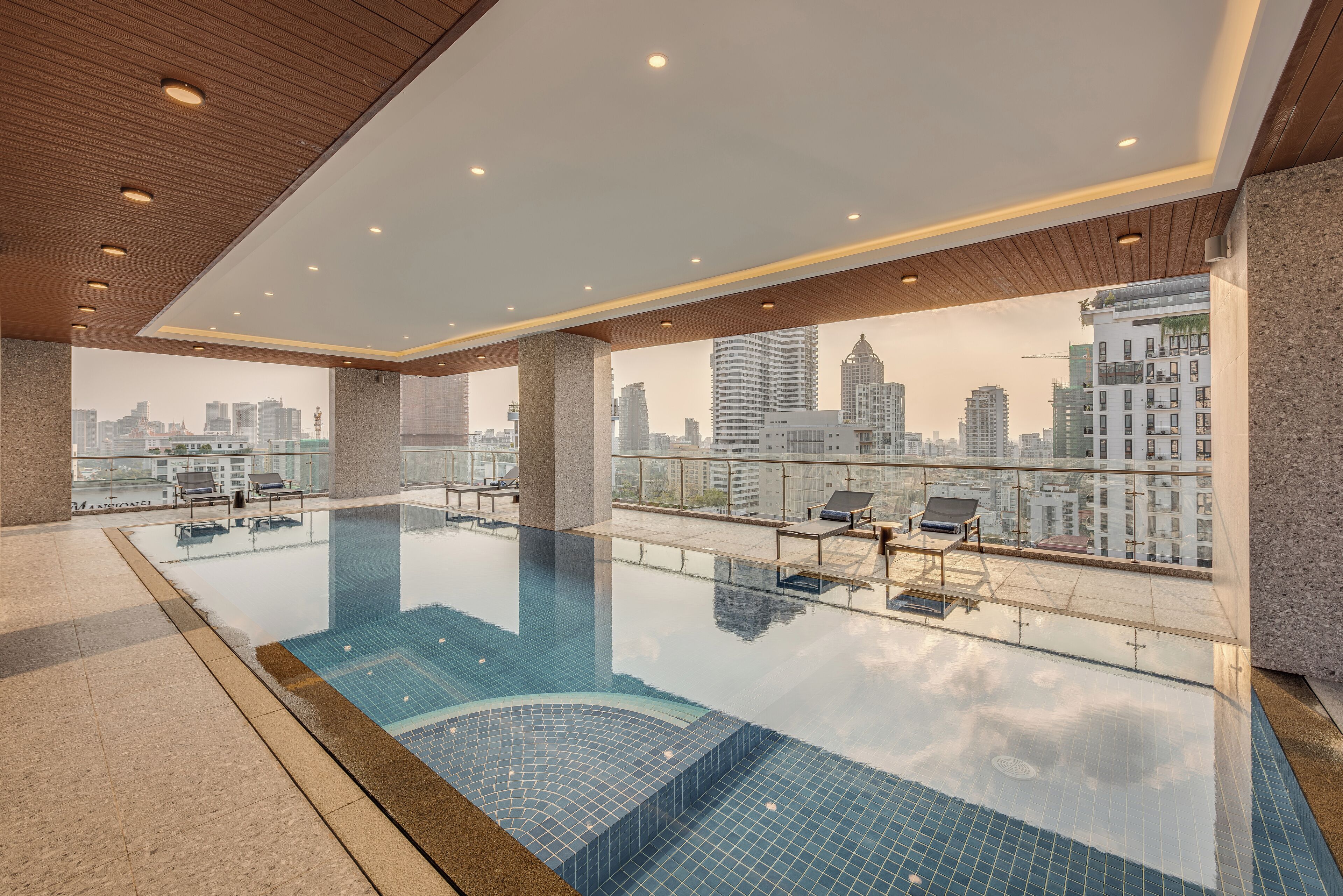 Una piscina infinita en la azotea con vistas a la ciudad, sillas de descanso y un diseño moderno.