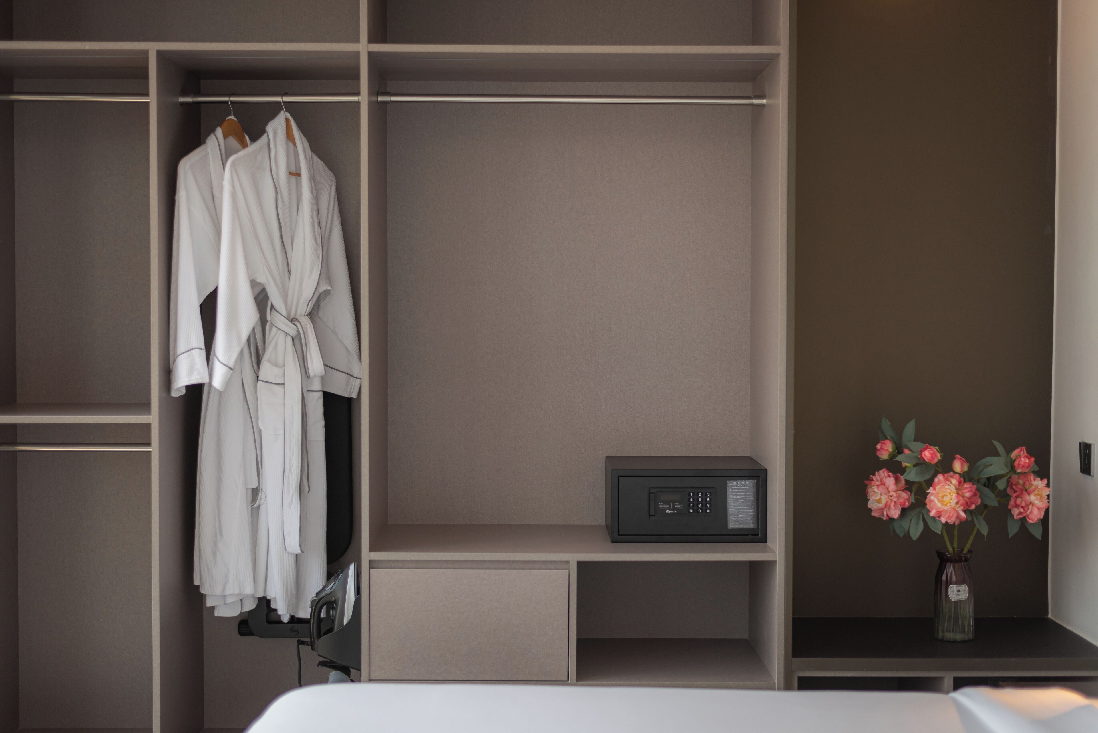 A modern room with a built-in wardrobe, a bedside table, and a vase with flowers.