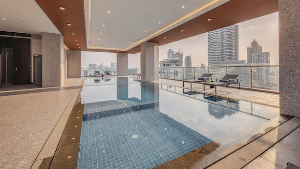 Una piscina interna moderna con vista sulla città, soffitto in legno e sedie a sdraio.