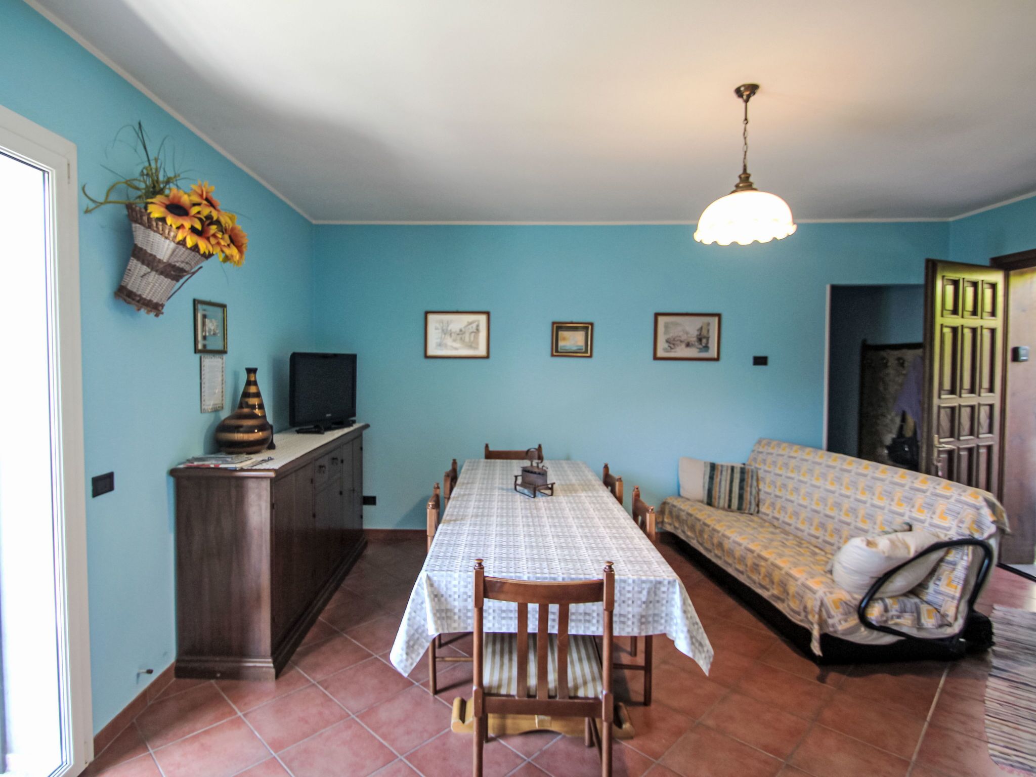 Un comedor con mesa, sillas, sofá y televisor sobre un mueble.