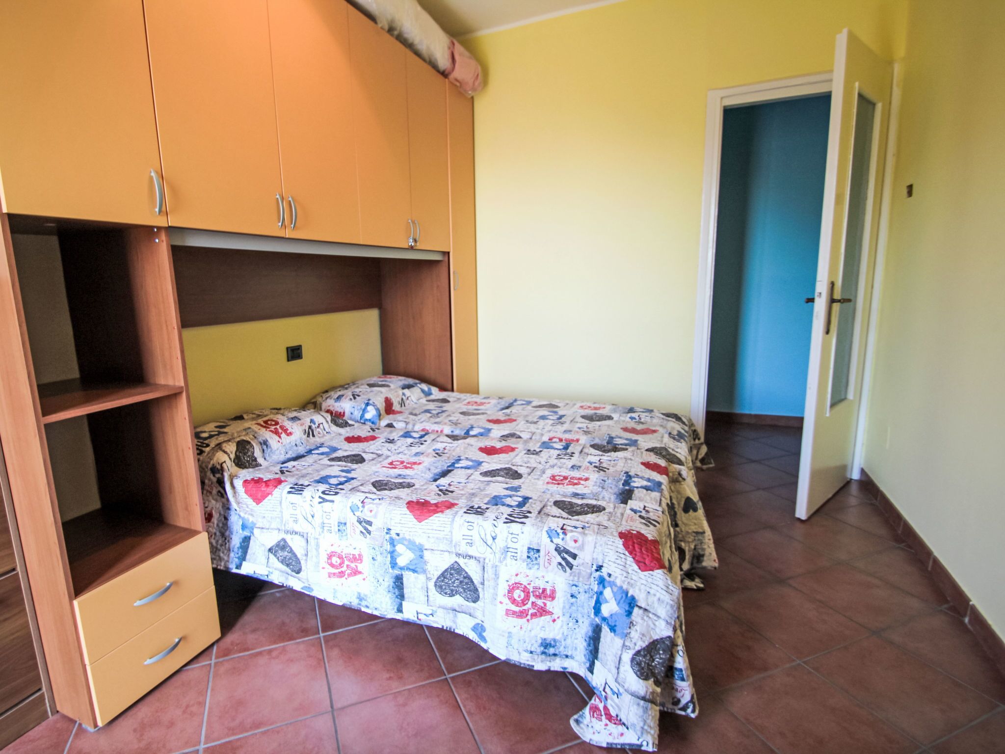 A bedroom with a bed, a wardrobe, and a door.