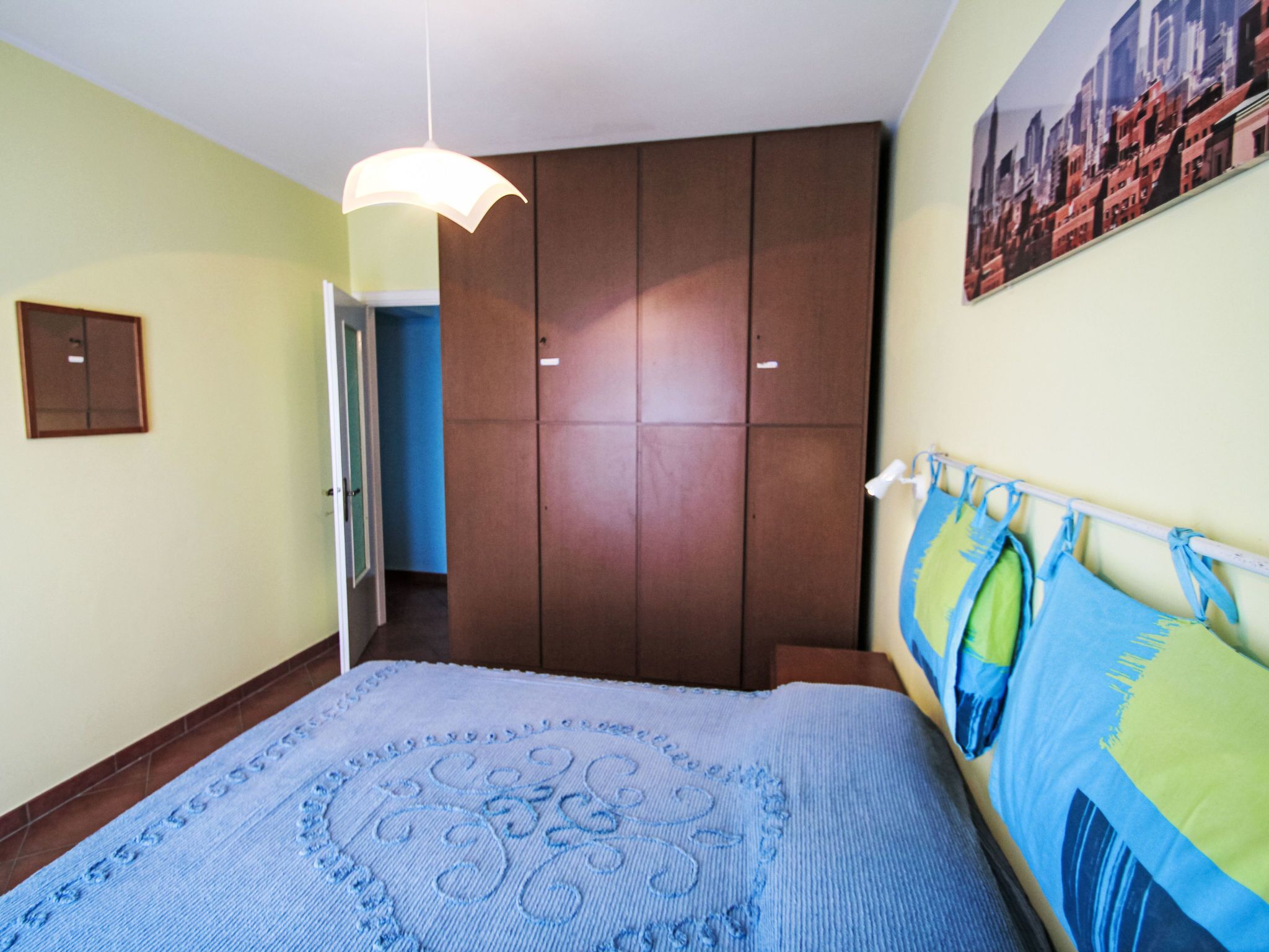 Une chambre à coucher avec un lit, une armoire, une porte et un mur orné d’un tableau.