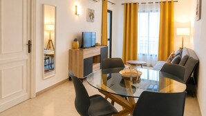 A modern living room with a glass dining table, comfortable seating, a flat-screen TV, and a large window with curtains. - Wonderful apartment at Ronda IV Fuengirola (Fuengirola)