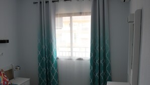 A bedroom with a bed, a bedside table, a dresser, and a window with curtains. - Wonderful apartment at Ronda IV Fuengirola (Fuengirola)