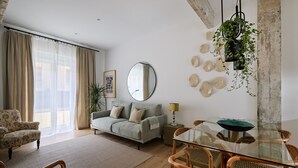 Un salon moderne avec un canapé, une table à manger et des chaises, un miroir et une plante suspendue.