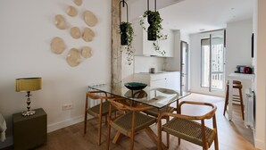 Un espace repas moderne avec une table en verre, des chaises en bois et des plantes suspendues.
