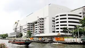 A modern building with multiple floors and balconies, a waterfront view, and a boat docked nearby.