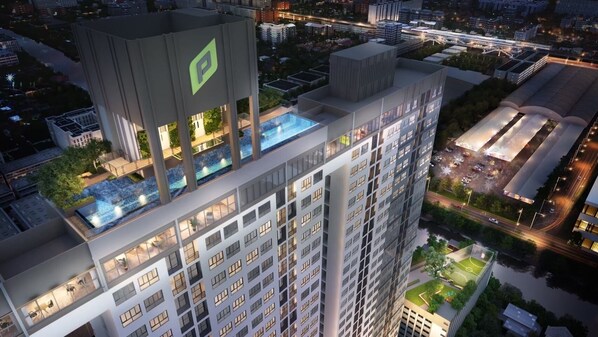 A high-rise hotel with multiple floors, a rooftop pool, and a parking area.