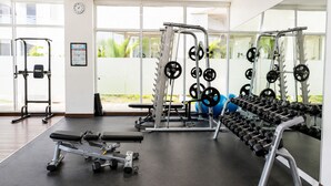 Une salle de sport équipée de matériel de musculation, d’un banc et d’un miroir.