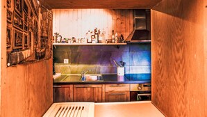 A compact kitchen with wooden cabinets, a stainless steel sink, and various kitchen appliances. - La Capsule by Interhome (Thyon-Les Collons)