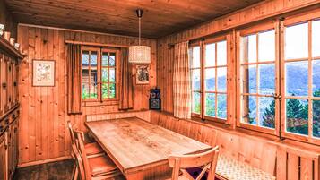Ein Holzblockbau-Innenraum mit einem großen Esstisch, Stühlen und einer Bank.