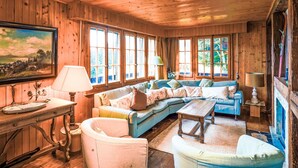 A cozy cabin interior with wooden walls, a large window, a sofa, a table, and a lamp. - La Capsule by Interhome (Thyon-Les Collons)