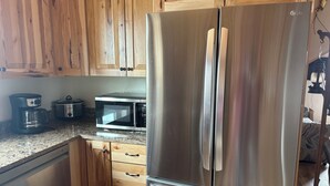 A kitchen with wooden cabinets, a stainless steel refrigerator, a microwave, and a coffee maker.