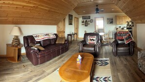 A cozy living room with a brown leather sofa, a patterned couch, and a wooden coffee table.