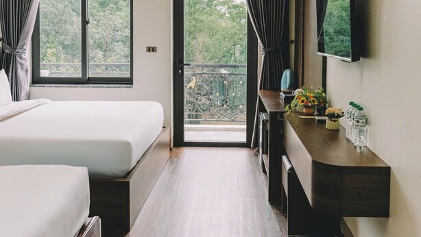 Une chambre d’hôtel comprenant un lit, un bureau avec un téléviseur à écran plat et un balcon avec des rideaux.