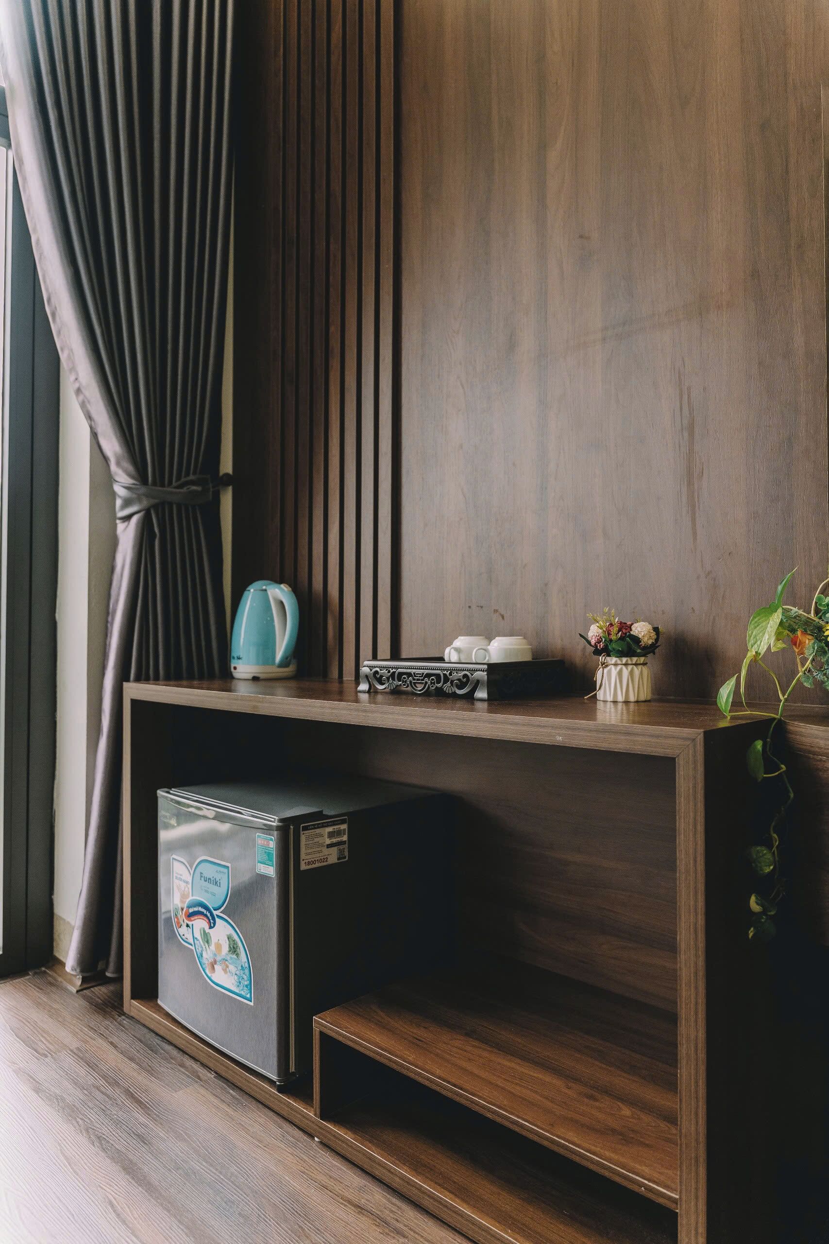 Une console en bois sur laquelle se trouvent une bouilloire, des tasses, un plateau et un petit vase avec des fleurs.
