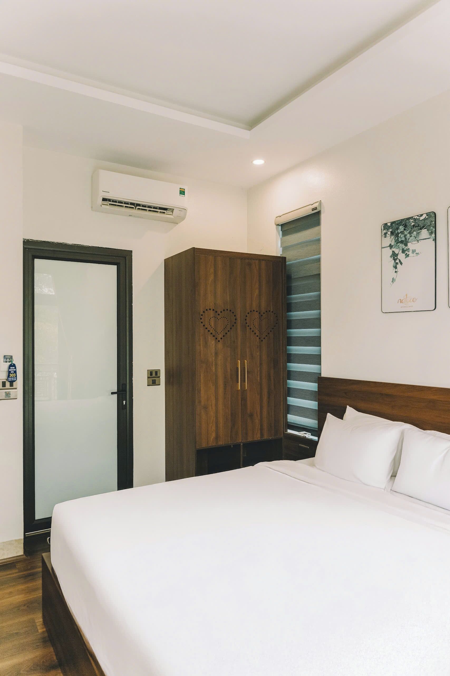 A hotel room with a bed, wardrobe, and an air conditioning unit.