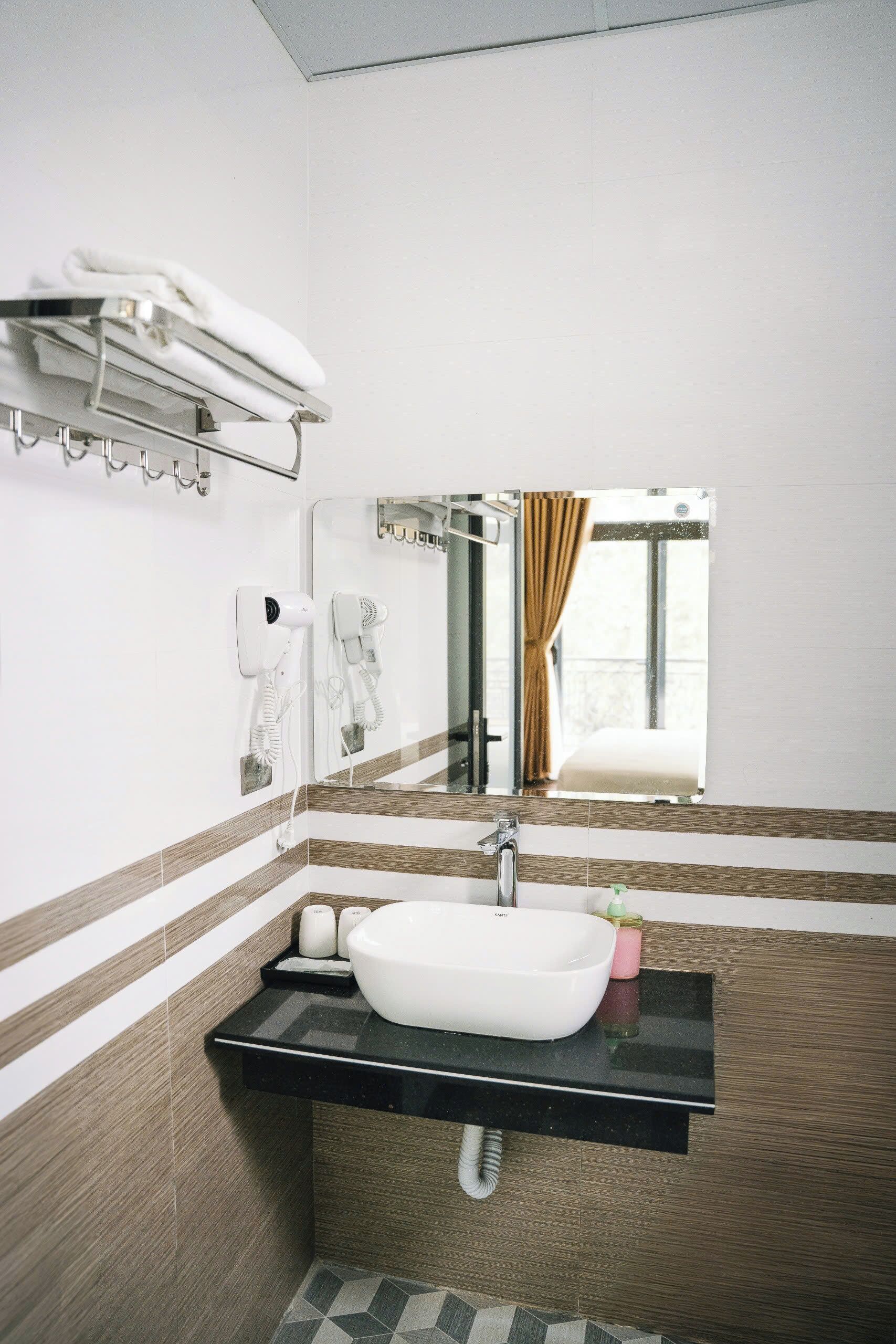 A modern bathroom with a large mirror, a white sink, and a towel rack.