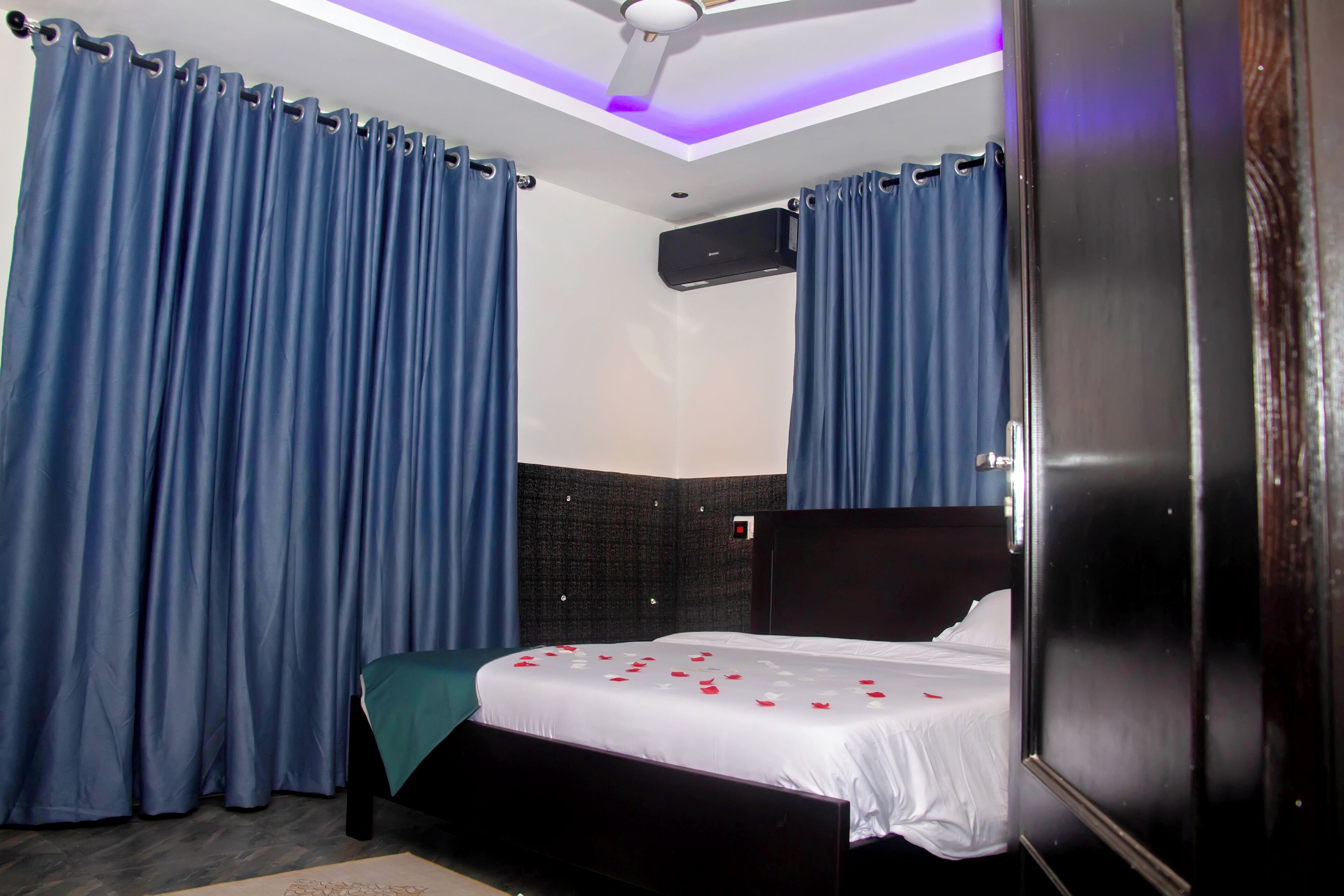 Une chambre à coucher avec un lit, des rideaux, un ventilateur de plafond et un appareil de climatisation.