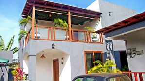 A two-story building with a balcony, a car parked in front, and a clear blue sky. - Royal Tulip Court (Accra)