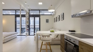 Een moderne keuken met een wit aanrecht, houten stoelen en een inbouwoven.