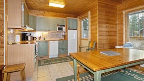 A wooden cabin interior with a kitchen, dining area, and a window providing a view of the outdoors. - Kevätruska a by Interhome (Kittilä)